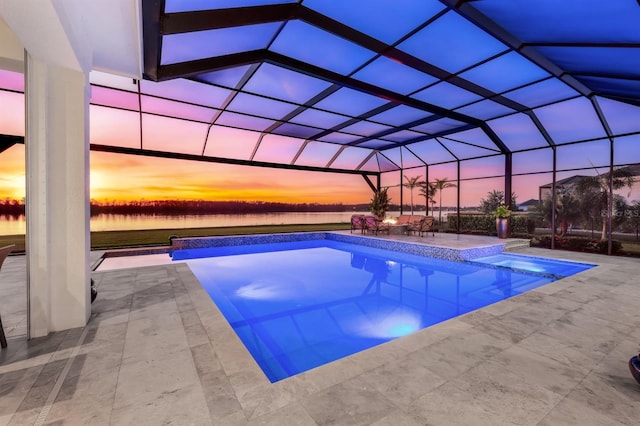 pool at dusk with a water view, glass enclosure, and a patio area