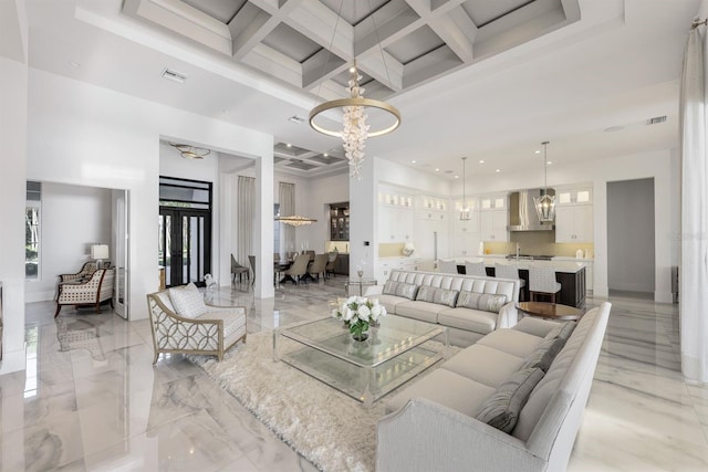 living room with beam ceiling, a high ceiling, coffered ceiling, and a notable chandelier