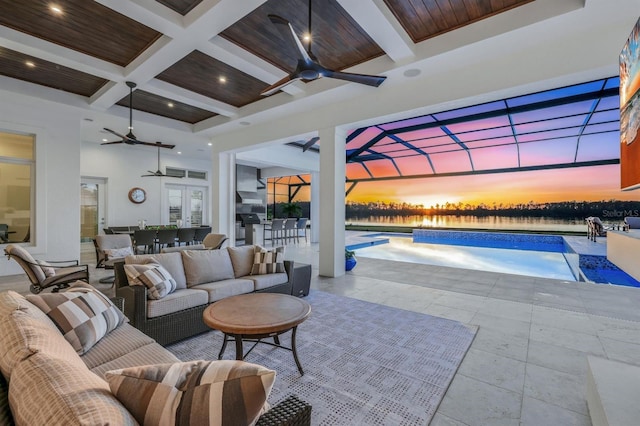 patio terrace at dusk featuring french doors, an outdoor living space, ceiling fan, and a lanai