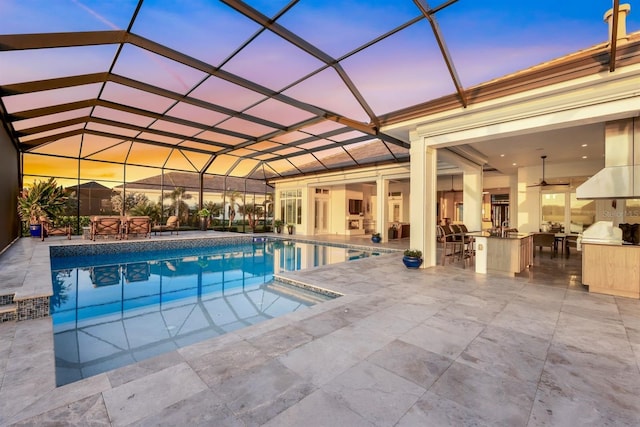 pool at dusk featuring a lanai, area for grilling, ceiling fan, and a patio