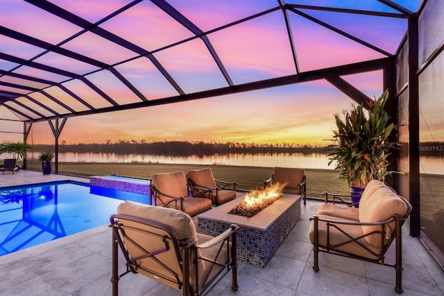 pool at dusk featuring an outdoor hot tub, an outdoor fire pit, a lanai, a patio area, and a water view