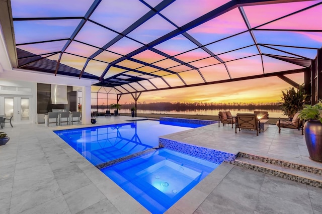 pool at dusk featuring a lanai, outdoor lounge area, an in ground hot tub, and a patio