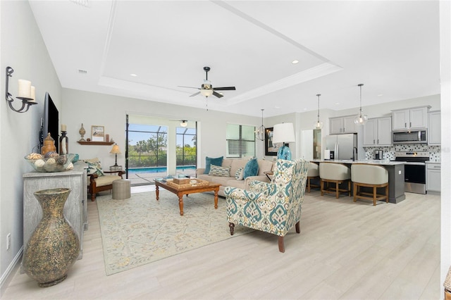 living room featuring ceiling fan, a raised ceiling, and light hardwood / wood-style flooring