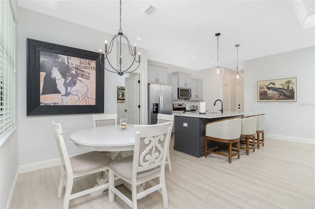 dining area featuring sink, a notable chandelier, and light wood-type flooring