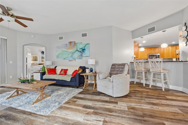 living room with ceiling fan and dark wood-type flooring