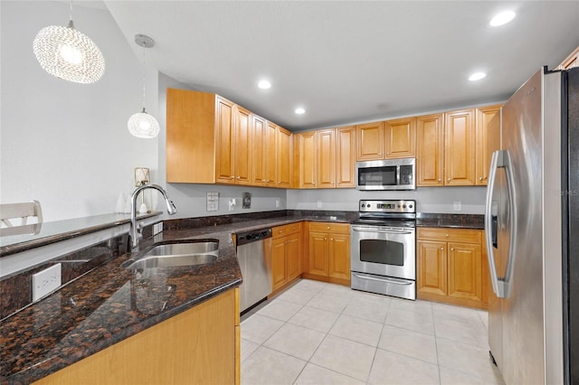 kitchen featuring sink, stainless steel appliances, hanging light fixtures, dark stone countertops, and kitchen peninsula