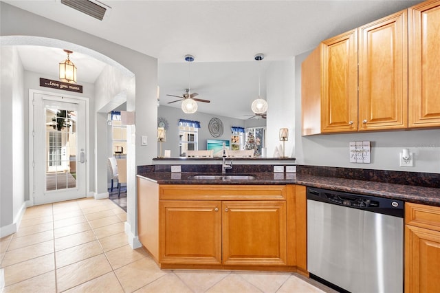 kitchen with dark stone counters, sink, stainless steel dishwasher, ceiling fan, and light tile patterned floors