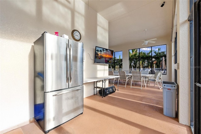 interior space with ceiling fan, stainless steel fridge, and a towering ceiling