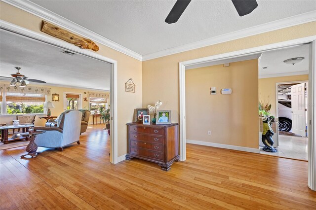 interior space featuring a fireplace, a textured ceiling, light hardwood / wood-style flooring, and crown molding