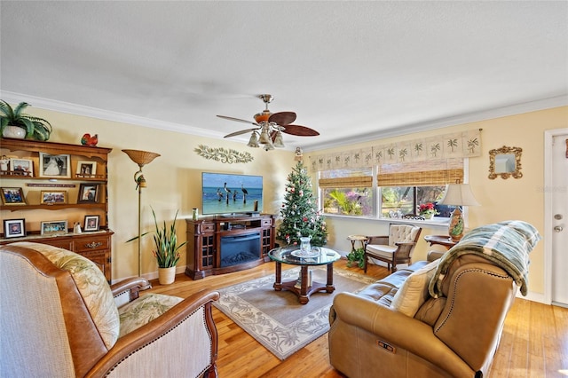 living room featuring a fireplace, light hardwood / wood-style floors, ceiling fan, and crown molding