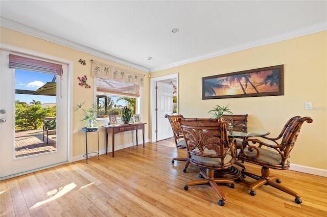 dining space with ornamental molding and light hardwood / wood-style flooring