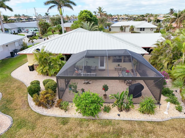 back of property with a lawn, glass enclosure, and a patio area