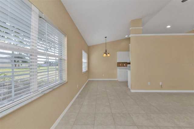 empty room with a notable chandelier, light tile patterned floors, and vaulted ceiling