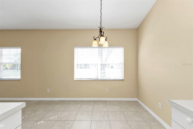 unfurnished dining area featuring light tile patterned floors and a chandelier