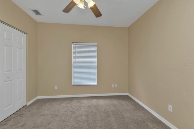 empty room featuring ceiling fan and light colored carpet