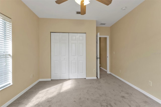 unfurnished bedroom featuring light carpet, a closet, and ceiling fan