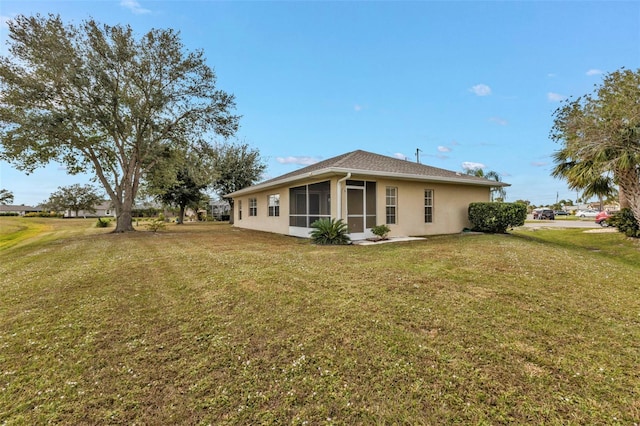 back of house featuring a sunroom and a lawn