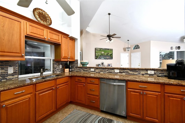 kitchen featuring dishwasher, dark stone counters, vaulted ceiling, and sink