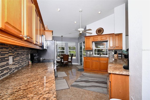 kitchen featuring ceiling fan, sink, light stone countertops, high vaulted ceiling, and decorative backsplash