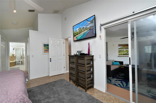 tiled bedroom with connected bathroom, ceiling fan, and a towering ceiling