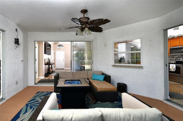 living room with ceiling fan and a textured ceiling