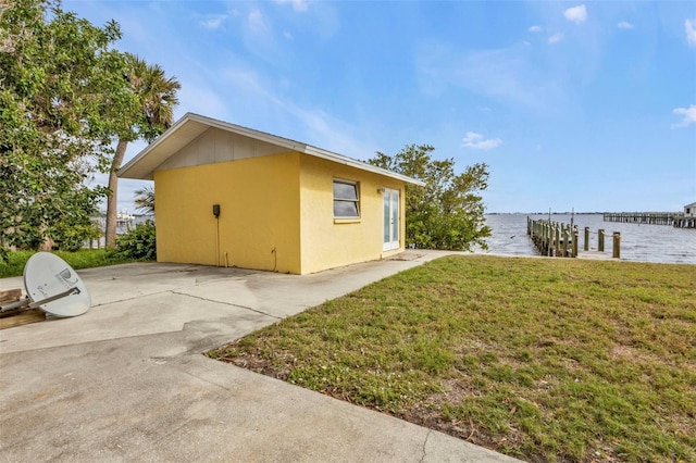 view of property exterior featuring a boat dock, a water view, and a yard