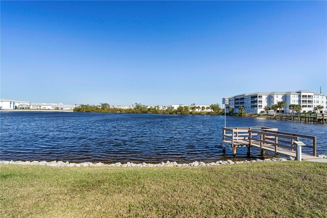 view of dock with a yard and a water view