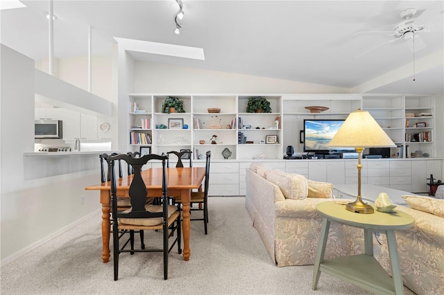 carpeted dining area with ceiling fan and lofted ceiling with skylight