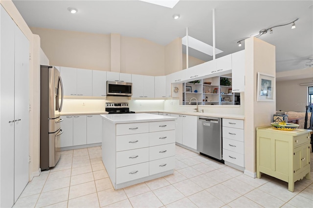 kitchen with white cabinetry, sink, light tile patterned floors, a kitchen island, and appliances with stainless steel finishes