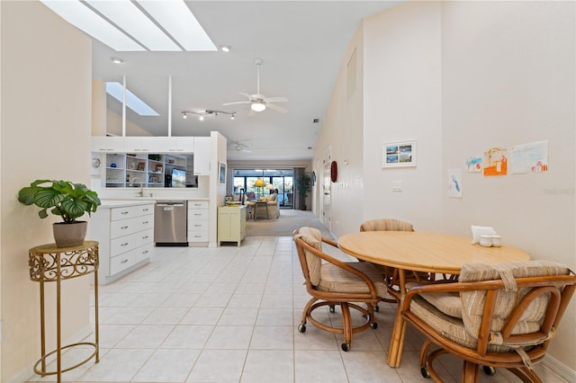 dining space featuring high vaulted ceiling, sink, a skylight, ceiling fan, and light tile patterned flooring