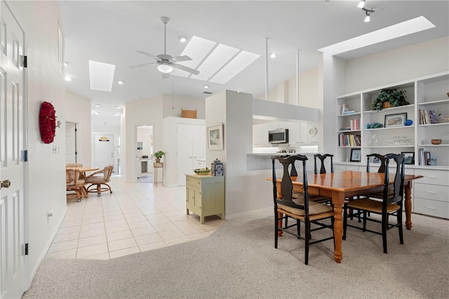 dining room featuring ceiling fan, light colored carpet, and a high ceiling