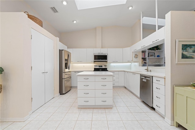 kitchen featuring a skylight, sink, stainless steel appliances, light tile patterned floors, and white cabinets