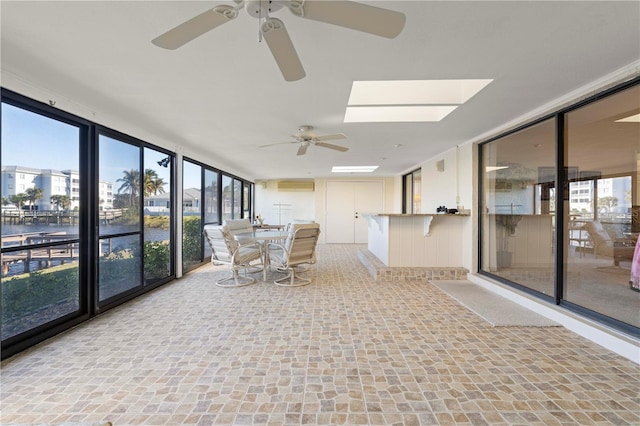 unfurnished sunroom with ceiling fan, a water view, and a skylight