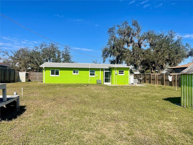 back of house with cooling unit and a lawn