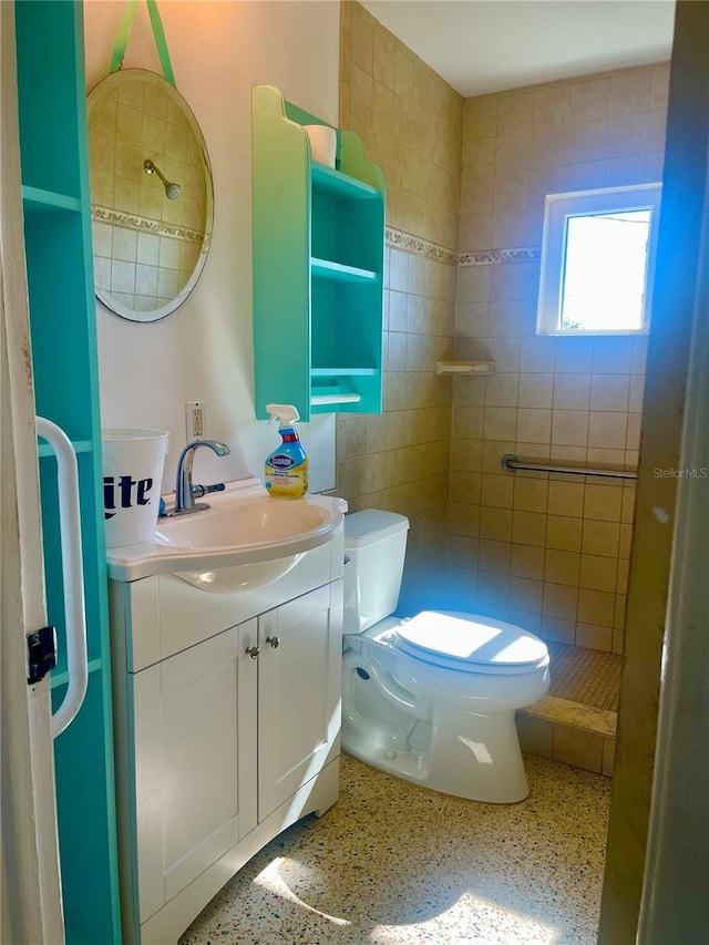 bathroom with vanity, tiled shower, and toilet