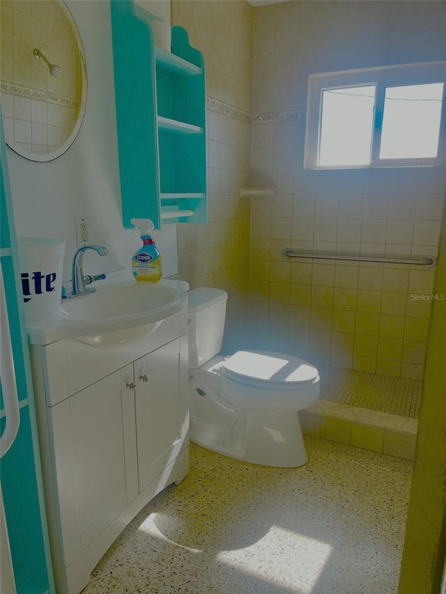 bathroom featuring vanity, tiled shower, and toilet