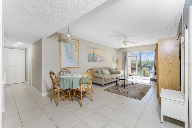 living room with ceiling fan, light tile patterned floors, and a textured ceiling