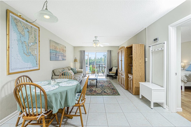 tiled dining area with ceiling fan and a textured ceiling