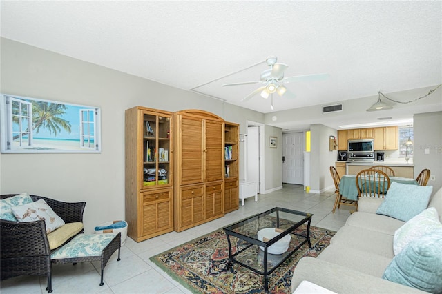 living room with light tile patterned floors, a textured ceiling, and ceiling fan