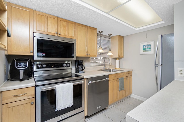 kitchen with light brown cabinetry, a textured ceiling, stainless steel appliances, sink, and light tile patterned floors