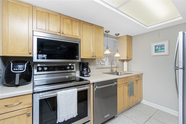 kitchen with sink, light tile patterned floors, a textured ceiling, appliances with stainless steel finishes, and decorative light fixtures