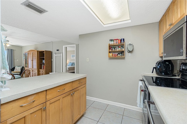 kitchen with a textured ceiling, white stove, ceiling fan, and light tile patterned flooring