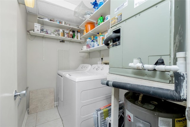 washroom with light tile patterned floors, water heater, and washing machine and clothes dryer