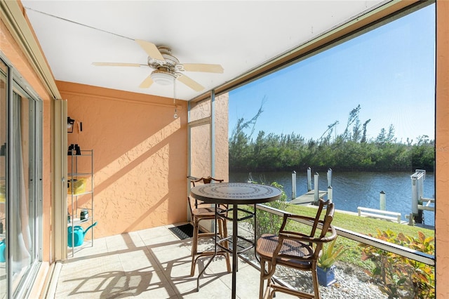 sunroom with a water view, ceiling fan, and a healthy amount of sunlight