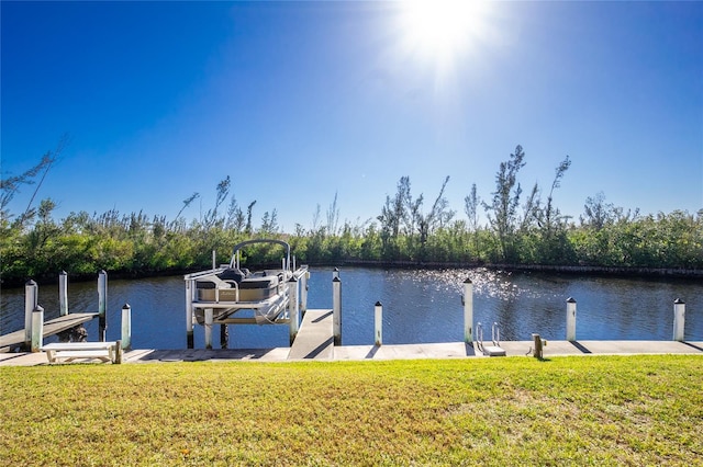 view of dock with a lawn and a water view