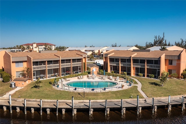 rear view of property with a lawn, a water view, and a community pool