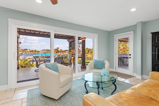 living room with ceiling fan and a water view