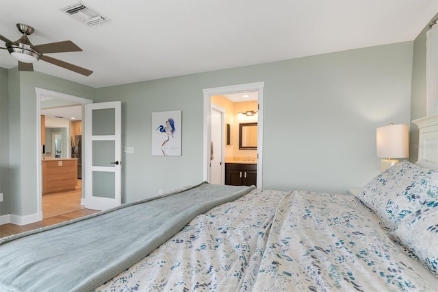 bedroom featuring stainless steel fridge with ice dispenser, ensuite bath, and ceiling fan