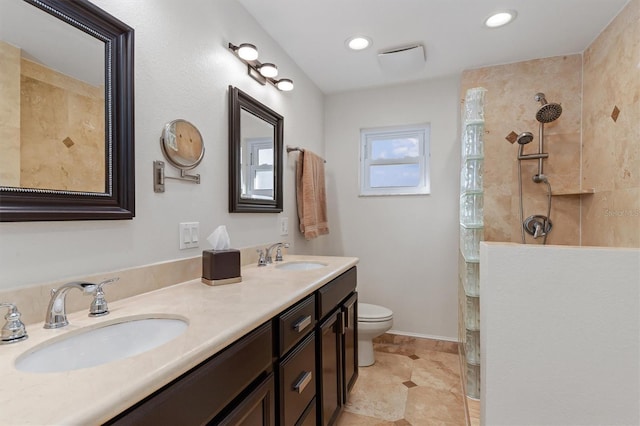 bathroom featuring a tile shower, vanity, and toilet