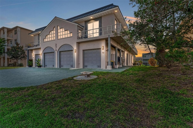 view of front facade featuring a garage, a balcony, and a yard